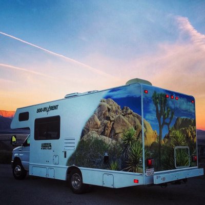 Cruise America RV on the road with sunset in the back ground and mountains