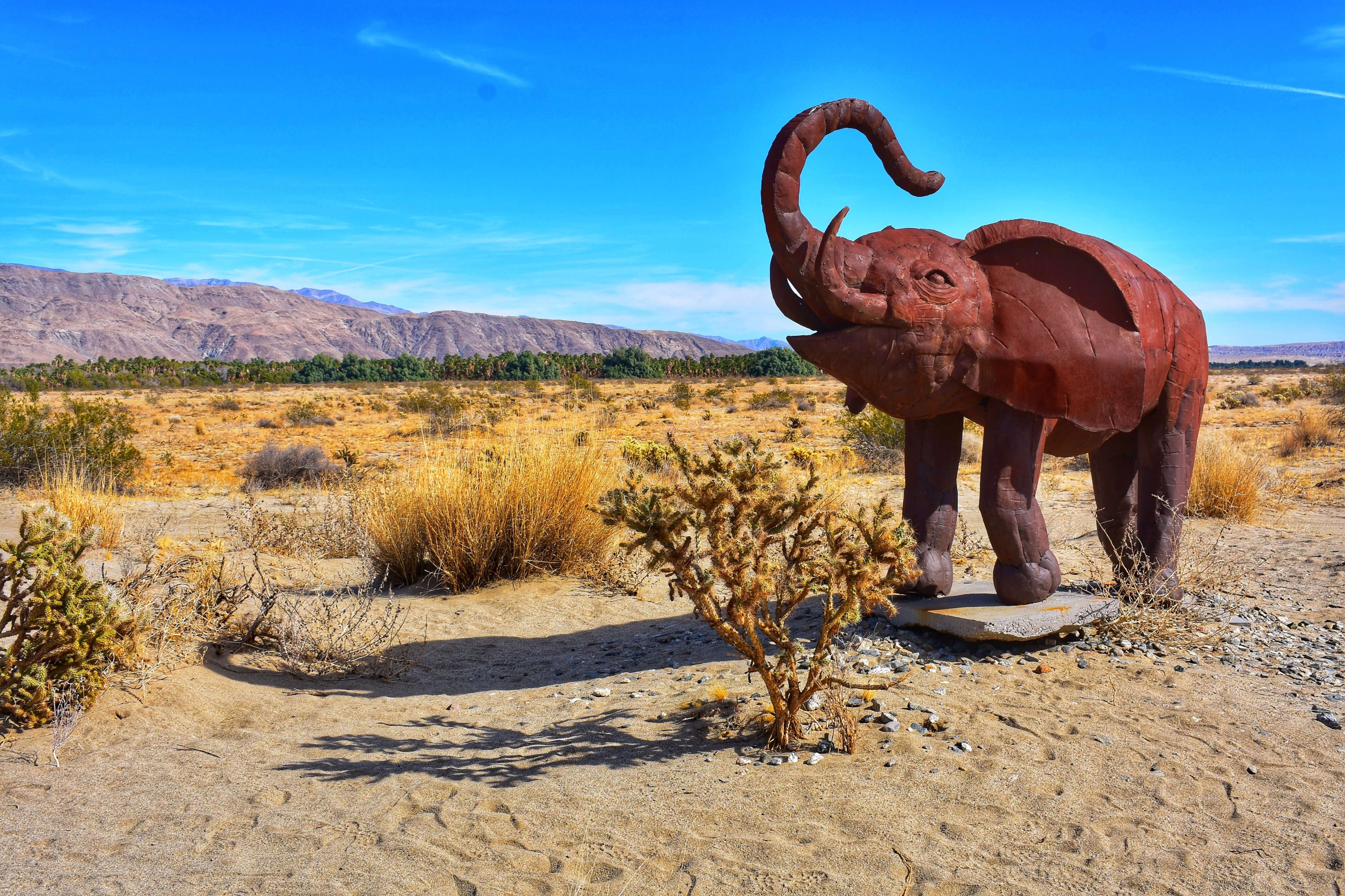 Desert with blue skys and a sculpture of an elephant