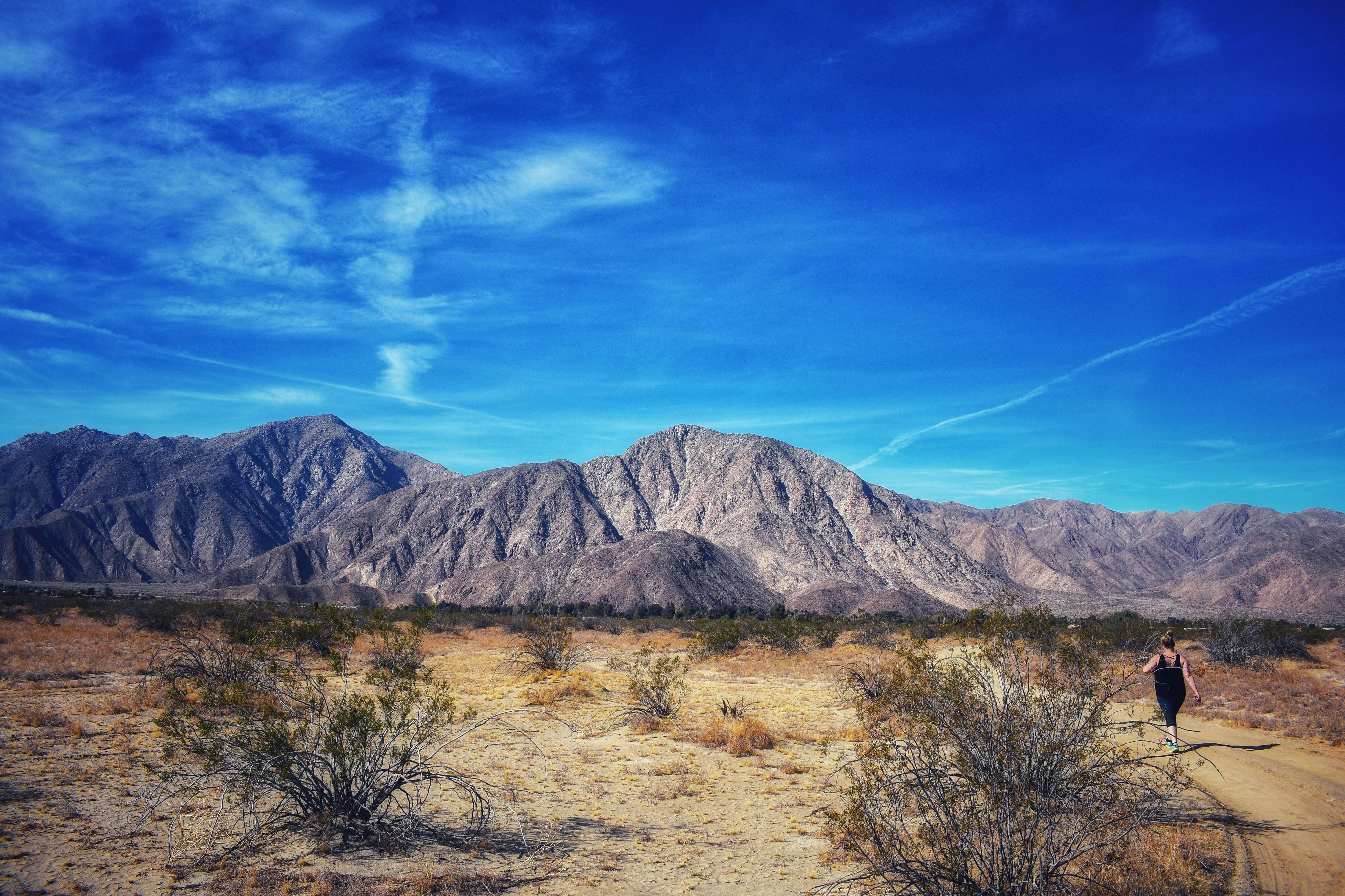 Girl walking alone in the vast desert with mountain in the background