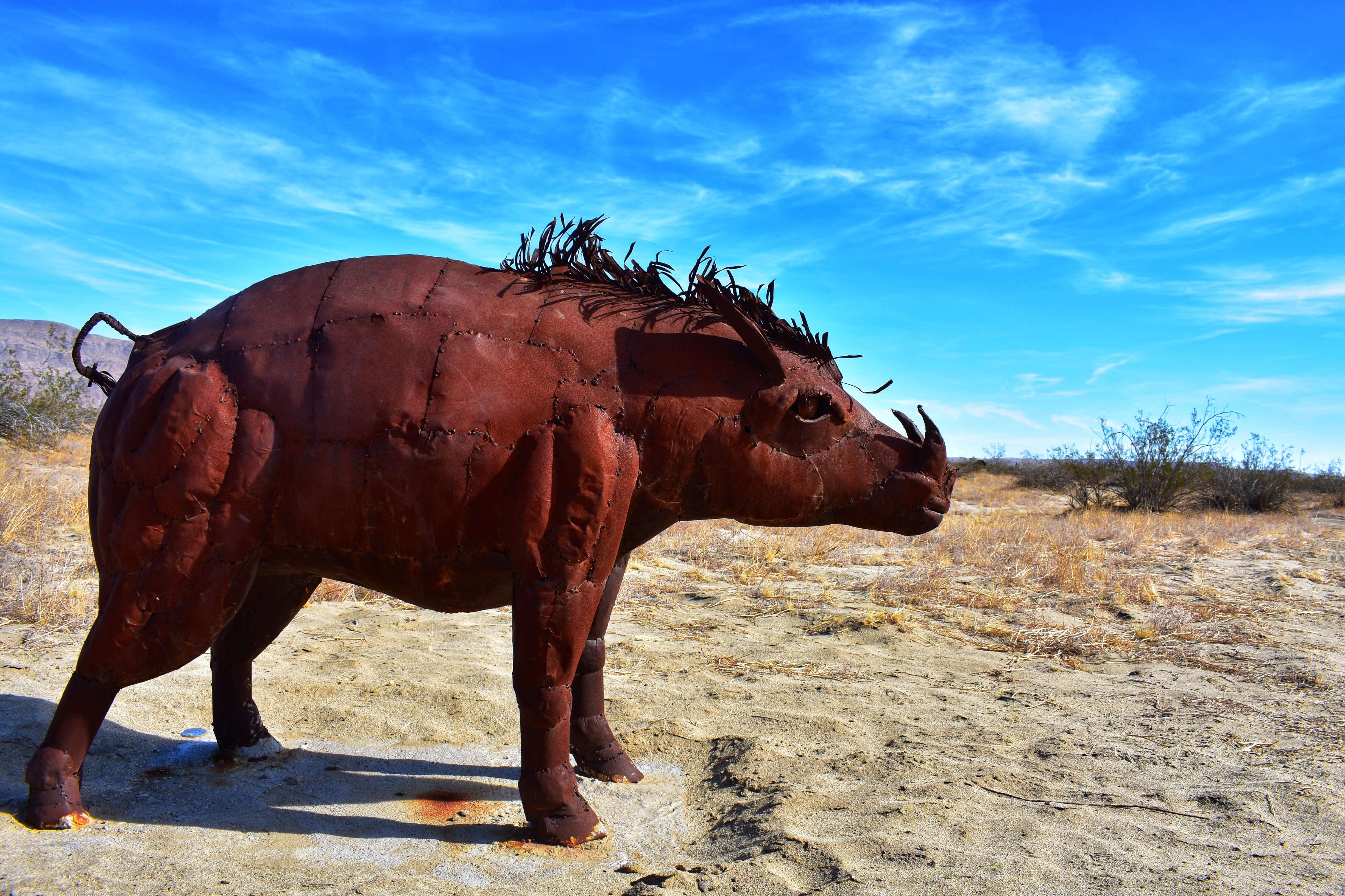 Boar sculpture in the middle of the desert, blue skies