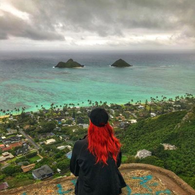 girl with red hair overlooking the ocean from atop a mountain