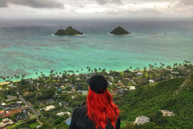 girl with red hair overlooking the ocean from atop a mountain