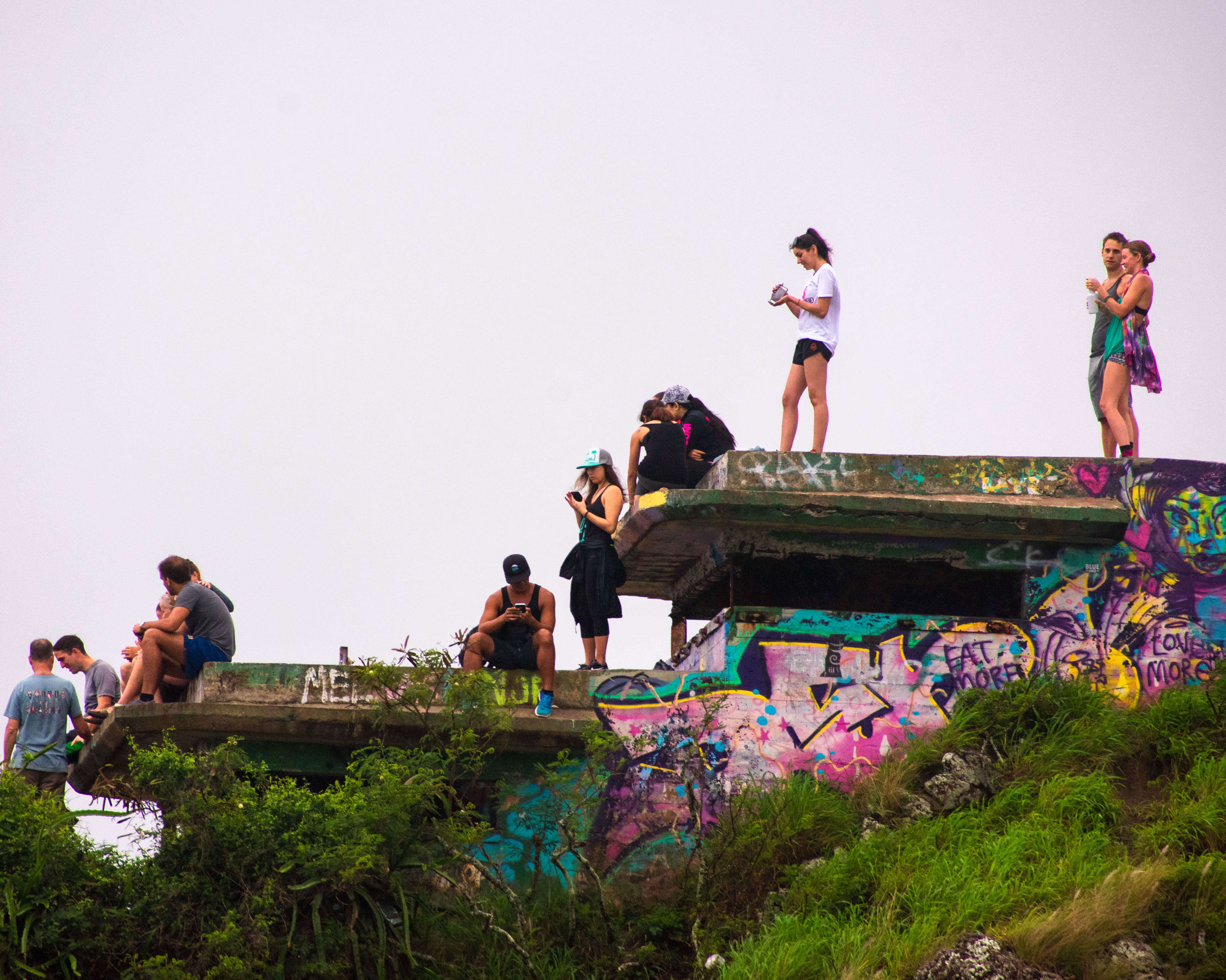 Hikers atop the 2nd pillbox on the Lanikai Pillbox hike, vibrant colored graffiti decorates the pillbox.