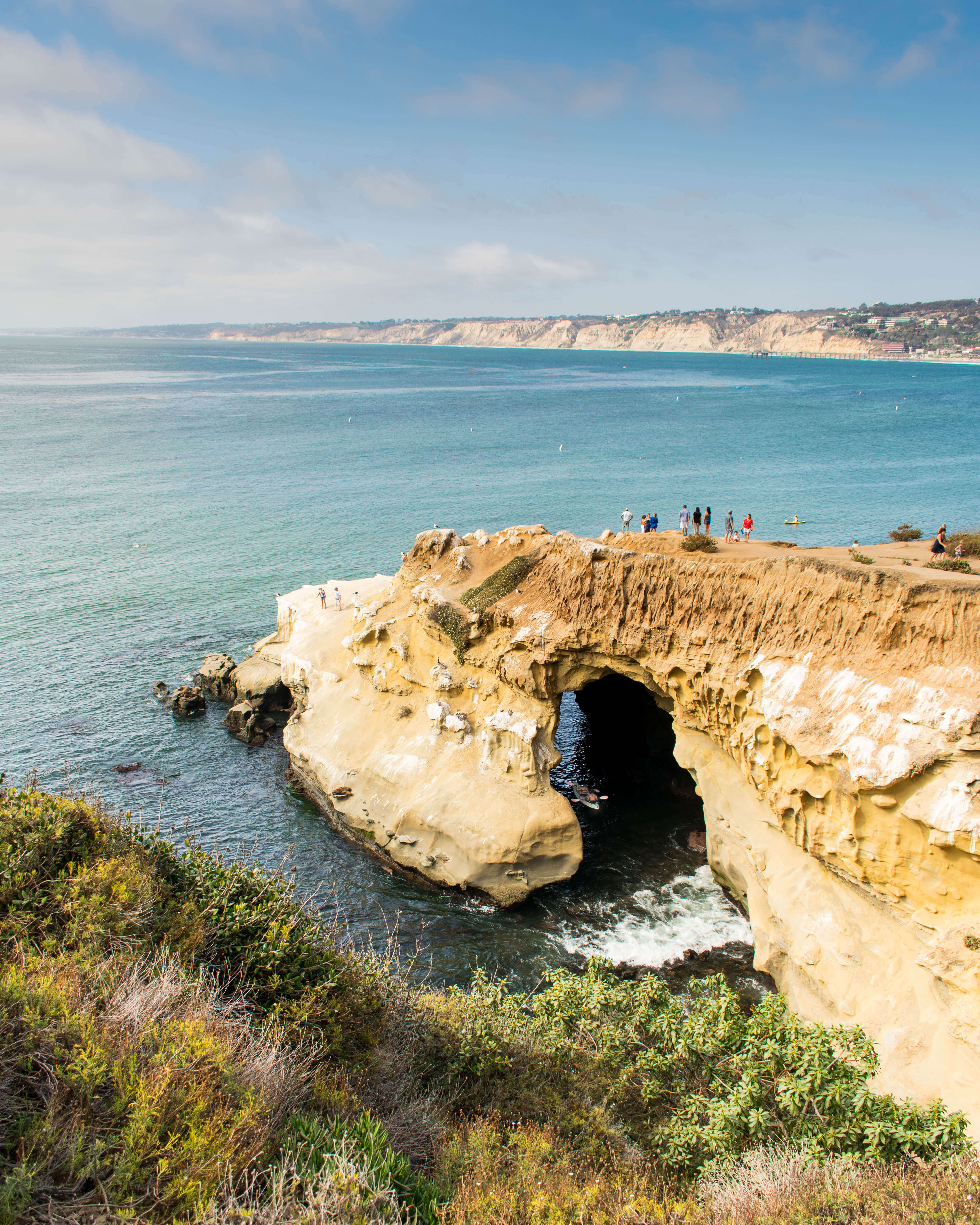 La Jolla coastline, you cans people on top of a sea cave and a kayak in the water