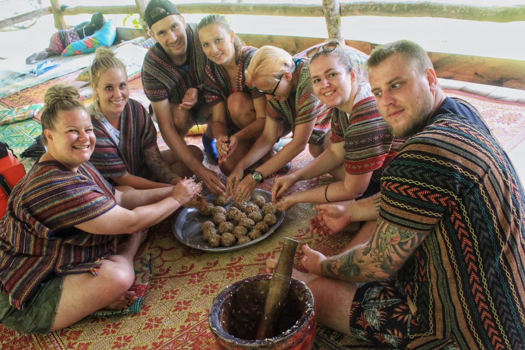 a group of people crowded around a plate making elephant medicine into balls for feeding