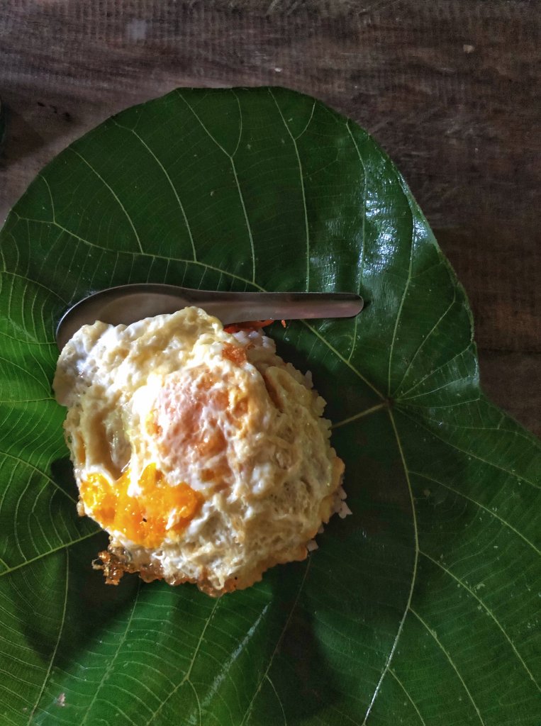 fried egg on top of sticky rice set on a huge green leaf