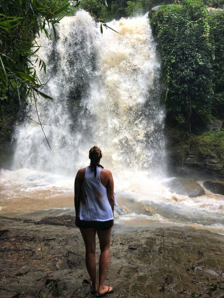 me standing on rocks looking at a huge waterfall crashing before me